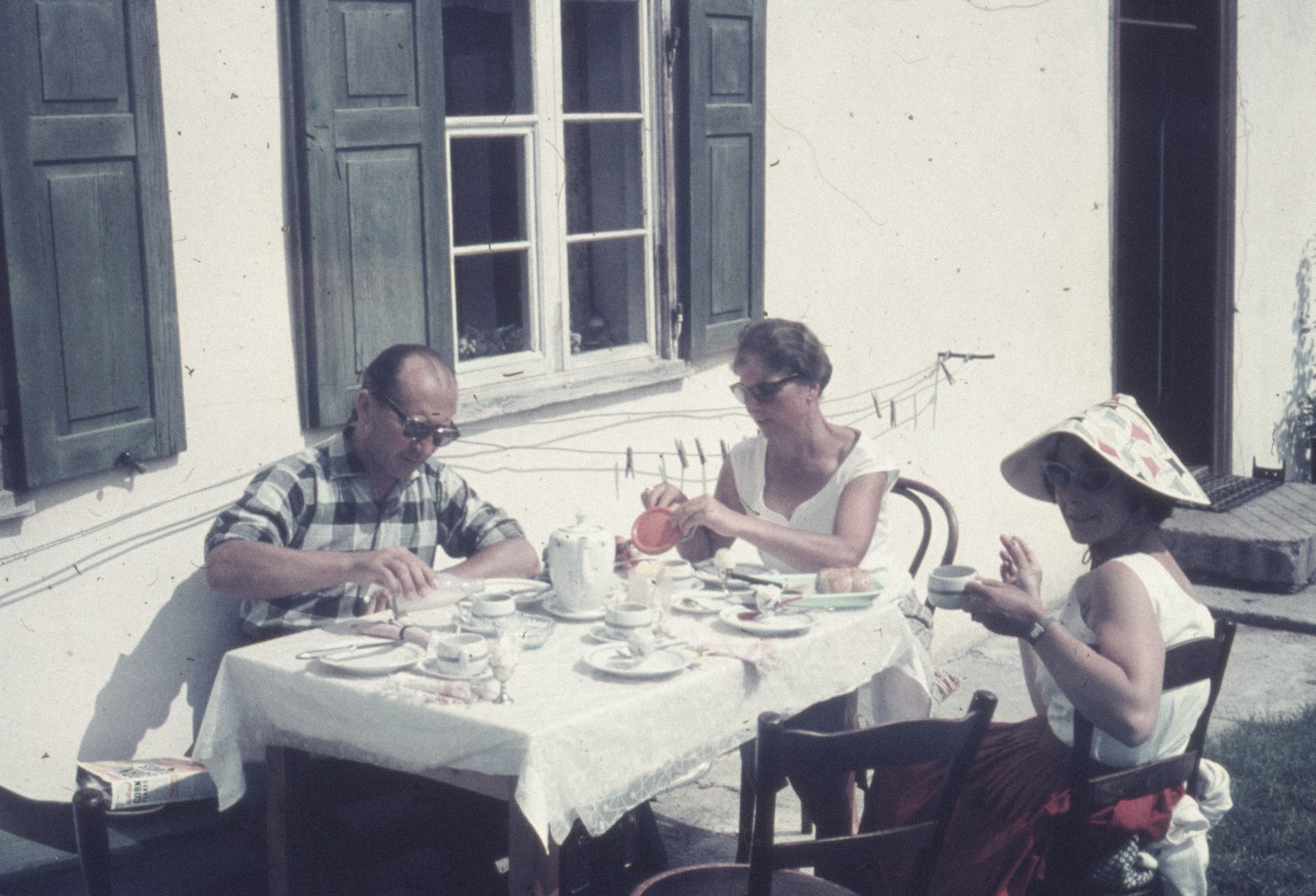 A vintage photograph of a couple and friend sharing breakfast outdoors